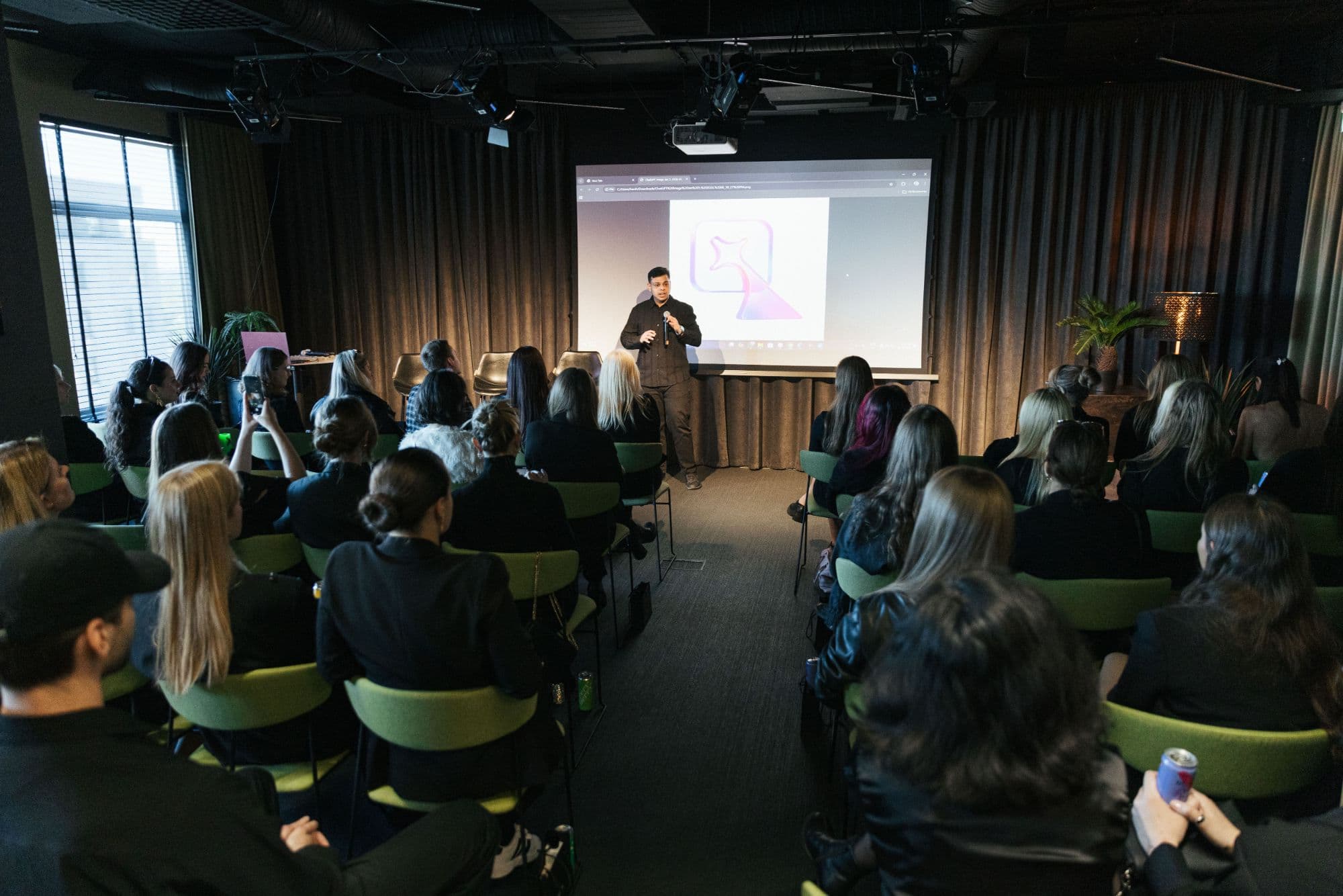 Harshul speaking to a full room at a Nexfluence event, the Nexfluence mark on the screen behind him.